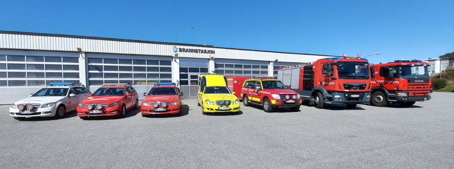 Utrykningskjøretøy oppstilt foran brannstasjon — brannbiler, ambulanse og utrykningsbiler